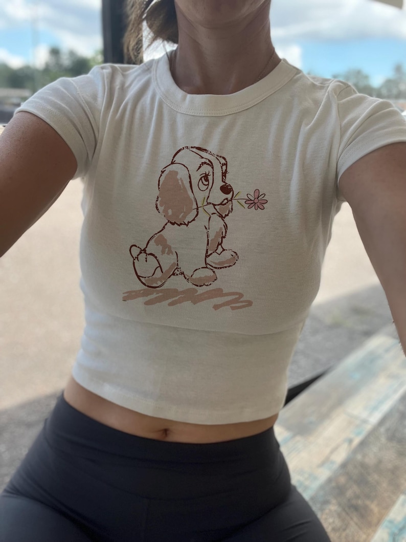 レディ・アンド・トランプのクロップタンク、パピーベビーTシャツ、映画版アメリカン・コッカー・スパニエル、レトロなディズニー・ドッグ、イングリッシュ・ドッグ、ディズニーワールドTシャツ、ディズニーランドTシャツ Cream Baby Tee
