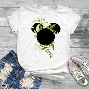 May include: White t-shirt with a black Mickey Mouse silhouette surrounded by green leaves and flowers.