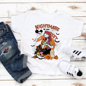 May include: White t-shirt with a graphic print of a character from the Nightmare Before Christmas movie. The text on the shirt says "Nightmare on Main Street".