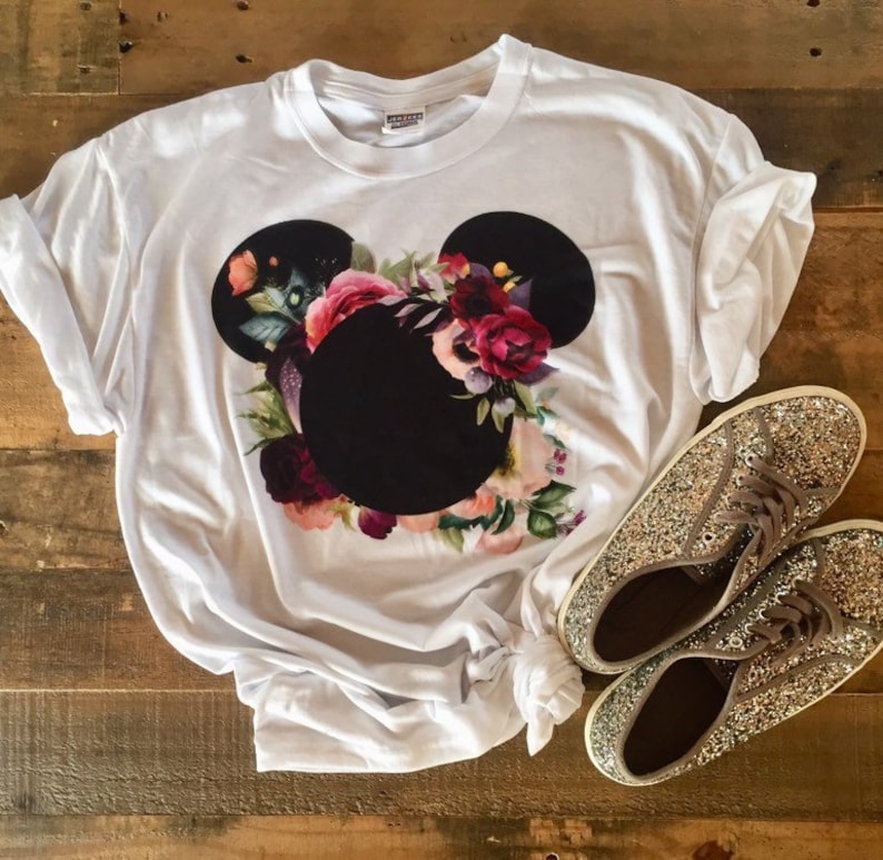May include: White t-shirt with a black floral Mickey Mouse design. The shirt is made of a soft, comfortable material.
