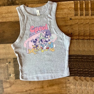 May include: Gray tank top with a colorful graphic featuring the word "Epcot" and cartoon characters. The sleeveless top is made of a soft material and is suitable for casual wear.