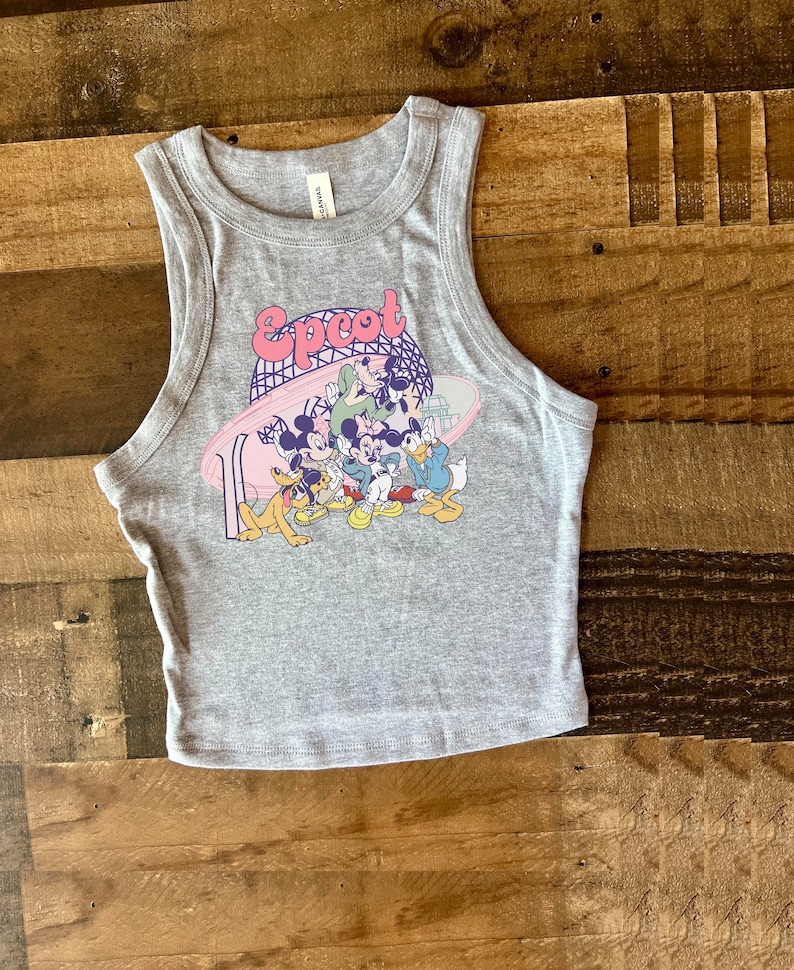 May include: Gray tank top with a colorful graphic featuring the word "Epcot" and cartoon characters. The sleeveless top is made of a soft material and is suitable for casual wear.