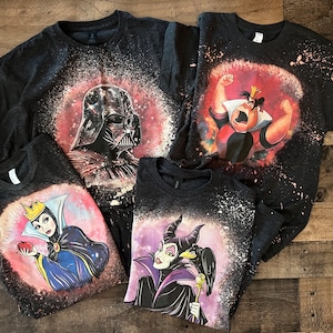 May include: Four black t-shirts with bleach-splattered designs featuring Disney villains. The shirts feature Darth Vader, the Queen of Hearts, Maleficent, and the Evil Queen.