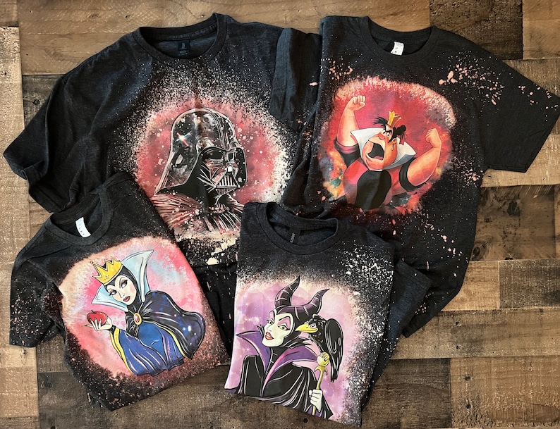 May include: Four black t-shirts with bleach-splattered designs featuring Disney villains. The shirts feature Darth Vader, the Queen of Hearts, Maleficent, and the Evil Queen.