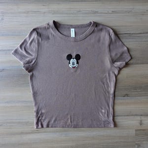 May include: A set of three ceramic mugs with a speckled, matte finish. The mugs are in shades of cream, light gray, and dark gray. Each mug has a simple, minimalist design and a rounded handle.