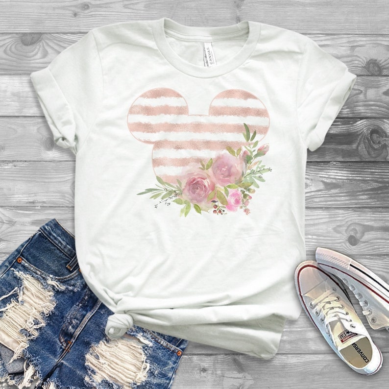 May include: White t-shirt with a pink and white striped Mickey Mouse head design and pink floral accents.