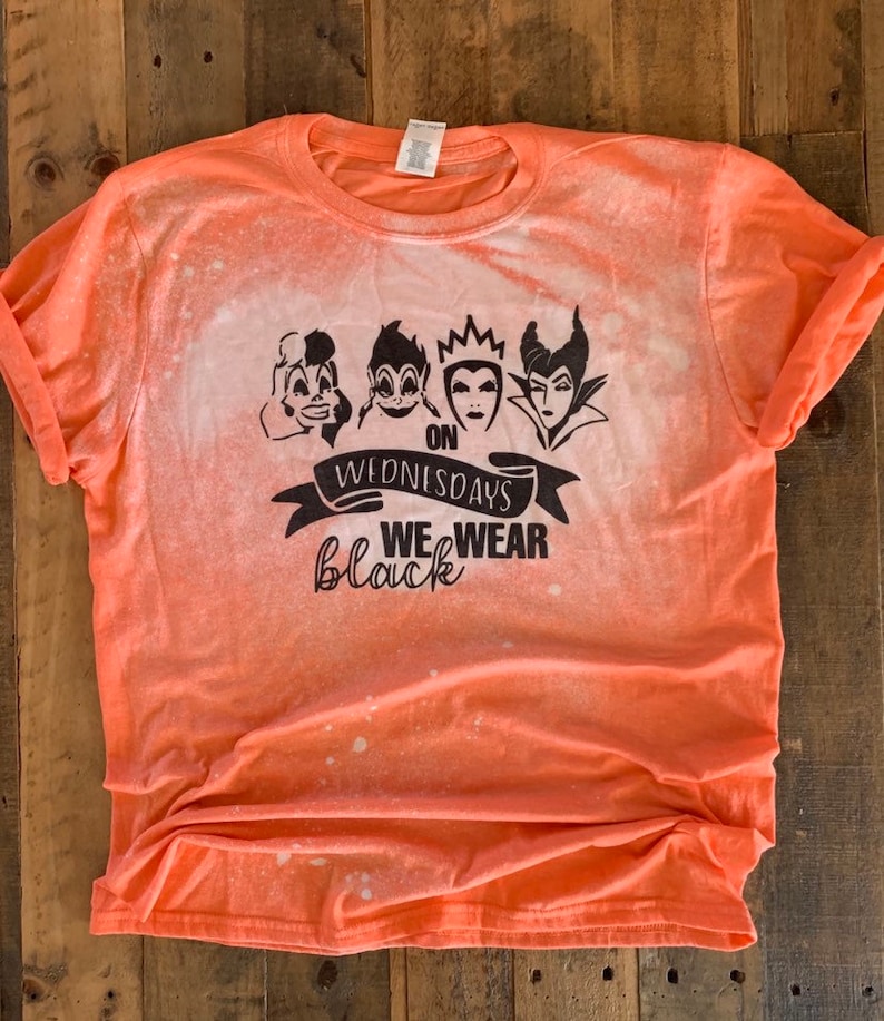 May include: Orange t-shirt with a bleach-splattered design. The shirt features a black graphic of four Disney villains with the text "On Wednesdays We Wear Black".