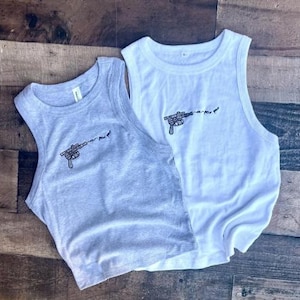 May include: A light gray tank top and a white tank top, both featuring a small black embroidered graphic of a ray gun firing a projectile with the text "pew pew" trailing from the barrel. Both garments have a ribbed crew neckline and sleeveless cut.
