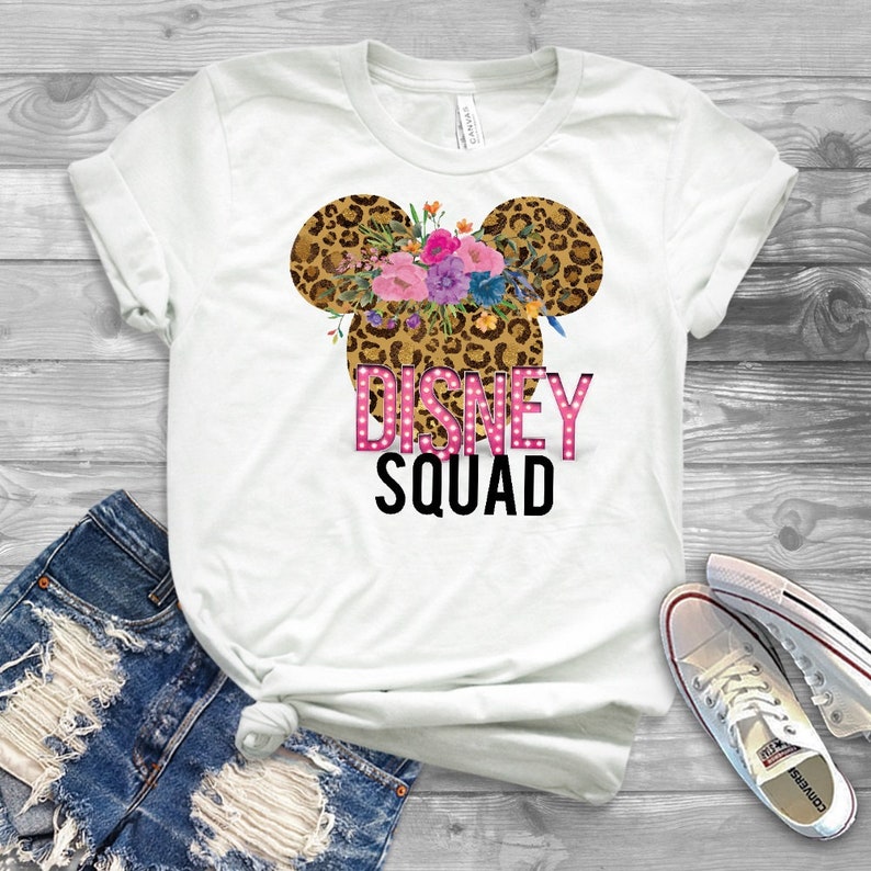 May include: White t-shirt with a leopard print Mickey Mouse ears with pink flowers and the text "DISNEY SQUAD" in pink letters.