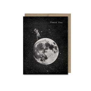 May include: A black and white greeting card with a celestial theme. The card features an illustration of a person on the moon with the text "Thank You". The card has a brown border.