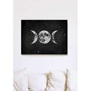May include: A black and white illustration of a triple moon symbol against a starry night sky background.