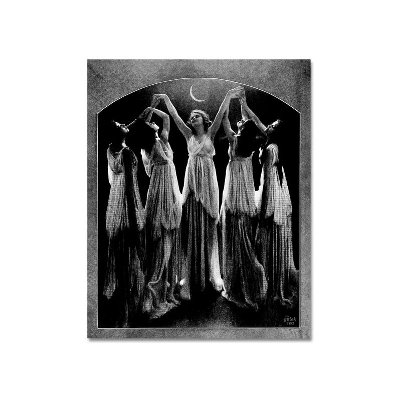 May include: Black and white photograph of five women in flowing robes dancing under a crescent moon. The women are silhouetted against a dark background, and their arms are raised in a graceful pose.
