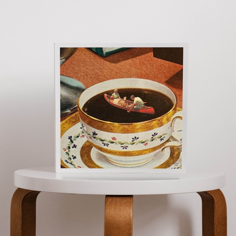 May include: A white teacup with gold trim and a floral pattern sits on a matching saucer. The teacup is filled with dark brown liquid, and a small red canoe with two figures paddling is floating on top.