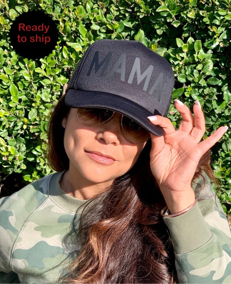 May include: Black trucker hat with a black mesh back and the word "MAMA" in large, bold, black letters.