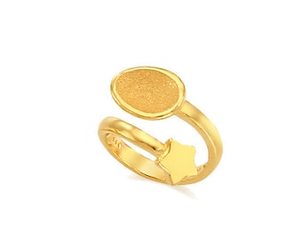 May include: A gold ring with a textured oval shape and a star design. The ring is open and adjustable.