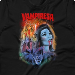K&ouml;nnte beinhalten: Schwarzes T-Shirt mit einem bunten Grafikdruck einer Vampirfrau mit einer Fledermaus und dem Text "Vampiresa" in Rot.
