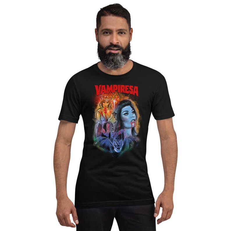 K&ouml;nnte beinhalten: Ein schwarzes T-Shirt mit einem grafischen Druck einer Frau mit roten Haaren und einer Frau mit blauen Haaren. Der Text "VAMPIRESA" ist in Rot auf dem Shirt gedruckt.