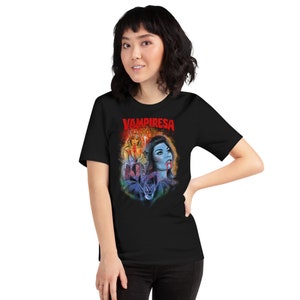 K&ouml;nnte beinhalten: Ein schwarzes T-Shirt mit einem Grafikdruck einer Frau mit roten Augen und blutigem Mund. Der Text "VAMPIRESA" ist in Rot &uuml;ber dem Grafikdruck gedruckt.