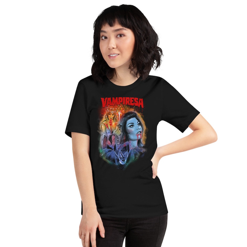 K&ouml;nnte beinhalten: Ein schwarzes T-Shirt mit einem Grafikdruck einer Frau mit roten Augen und blutigem Mund. Der Text "VAMPIRESA" ist in Rot &uuml;ber dem Grafikdruck gedruckt.