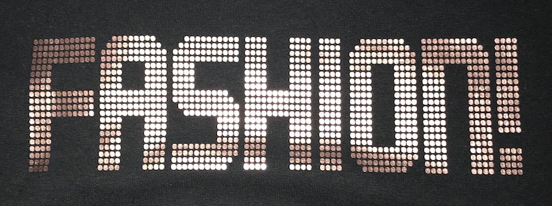 May include: The word FASHION! is displayed in a bold, block-letter font on a solid black background. The letters are constructed from a grid of small, metallic, copper-colored square studs that create a reflective, textured appearance.