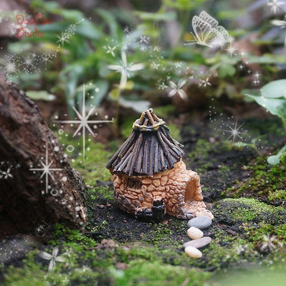 石造りの家のミニチュア、小さな枝の屋根のコテージの黄色/灰色の石の 