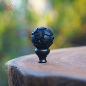 Peut inclure: Une sphère en bois noir avec un motif géométrique sculpté repose sur une base en bois noir. La sphère mesure environ 2,5 cm de diamètre.