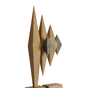 May include: A wooden sculpture with three geometric shapes, two are light brown and one is a darker blue-grey. The sculpture is on a wooden base.