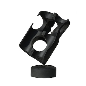 Puede incluir: Una escultura abstracta negra con una superficie texturizada. La escultura está hecha de metal y tiene una forma cilíndrica con dos grandes agujeros. Está montada sobre una base negra.