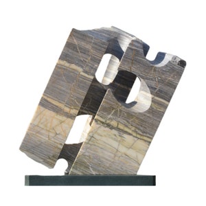 Puede incluir: Escultura abstracta hecha de mármol gris y blanco con un diseño geométrico. La escultura está sobre una base negra.