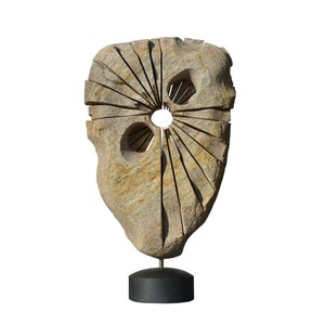 Puede incluir: Una escultura de piedra con una abertura circular en el centro y un patrón de líneas radiantes. La escultura está montada sobre una base negra.