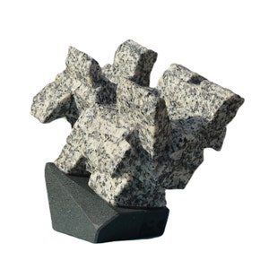 Puede incluir: Escultura abstracta hecha de granito gris y blanco, con un diseño geométrico. La escultura está montada sobre una base de granito negro.