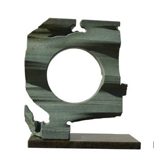 Puede incluir: Una escultura de piedra verde con una abertura circular en el centro. La escultura está sobre una base marrón oscuro.