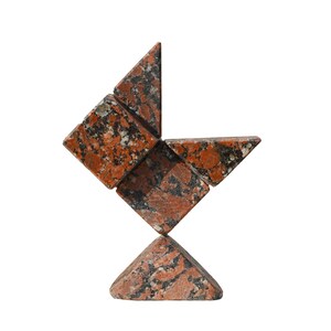 Puede incluir: Una escultura de granito rojo y negro hecha de formas geométricas. La escultura está equilibrada sobre una base triangular.