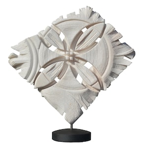 Puede incluir: Escultura de mármol blanco de diseño geométrico con forma de estrella de cuatro puntas. La escultura está sobre un pedestal negro.