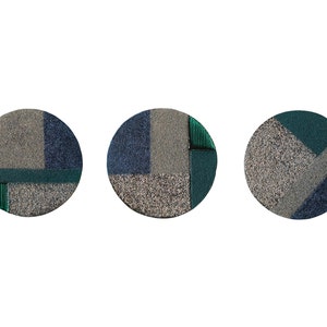Könnte beinhalten: Drei runde Wanddekorationen mit einem geometrischen Muster in Grautönen, Blau und Grün.