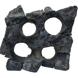 Puede incluir: Una escultura de piedra gris oscuro, toscamente labrada, con cuatro aberturas circulares. La piedra tiene una superficie texturizada y parece estar rota en varios pedazos, creando un diseño abstracto. Los agujeros están espaciados uniformemente.