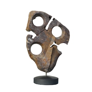 Puede incluir: Una escultura de piedra marrón y gris con cuatro aberturas circulares. La escultura está montada sobre un pedestal negro.