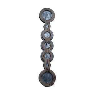 Puede incluir: Un adorno de pared vertical de madera con cinco recortes circulares dispuestos en columna. El marco está construido con madera teñida de marrón oscuro con veta visible, mientras que el interior de cada círculo contiene un inserto circular gris.