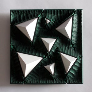 May include: A dark green square wooden wall art piece with a textured surface. The piece features six white triangular shapes that are raised and appear to be floating on the surface.