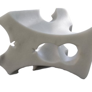 Puede incluir: Una escultura abstracta de mármol blanco con varios agujeros y curvas.
