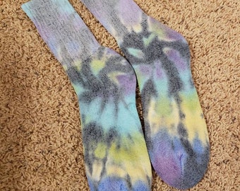May include: A pair of tie-dye socks in shades of blue, purple, yellow, and black. The socks are made of cotton and have a crew length.