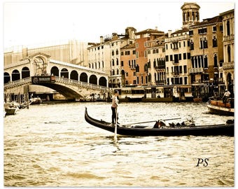 Puede incluir: Una fotografía en sepia de una góndola en un canal de Venecia, Italia. La góndola está siendo remada por un gondolero que lleva una camisa a rayas. El Puente de Rialto está en el fondo.