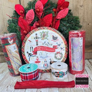 May include: A festive Christmas wreath with red poinsettias and a decorative plate featuring the "12 Days of Christmas" design. Includes rolls of Deco Poly Mesh, plaid ribbon, and a ribbon with a nutcracker design.