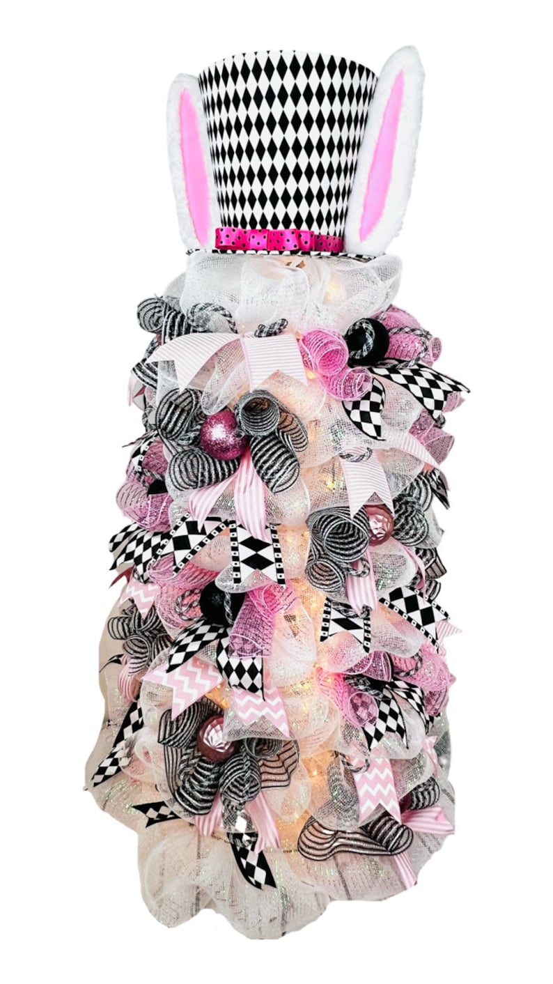 May include: A pink and black checkered bunny-themed tabletop tree with white mesh, pink and black ribbon, and white lights.