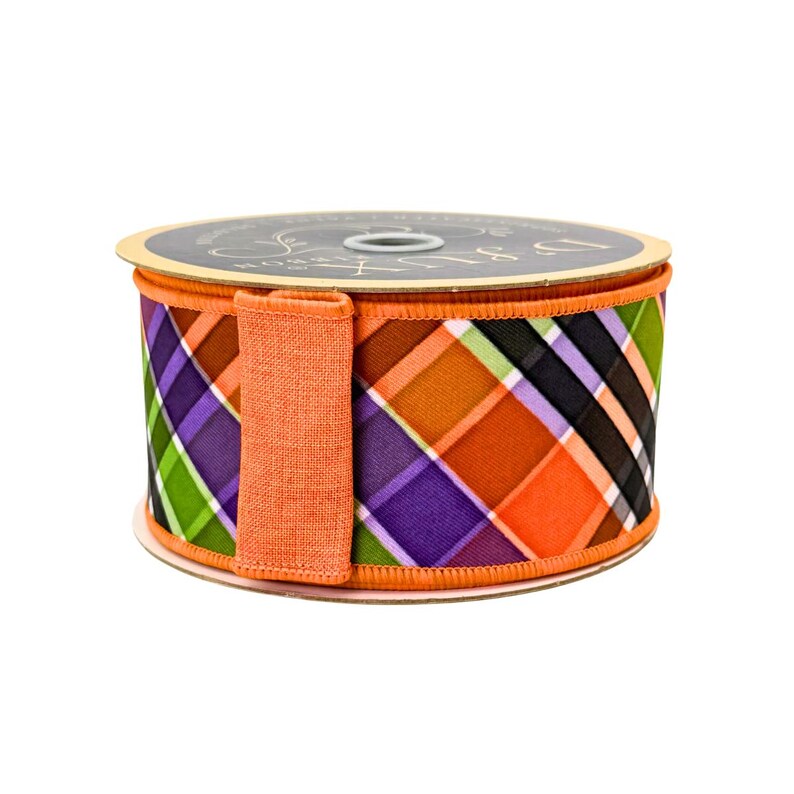 May include: A spool of decorative ribbon with a plaid pattern in orange, purple, green, and black. The ribbon has an orange fabric loop attached to the side. The spool is on a white background.