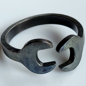 May include: A black metal ring shaped like two wrenches, joined together.