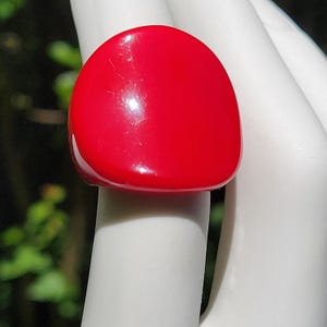 May include: A large, bright red ring with a smooth, rounded surface. The ring is made of plastic and has a glossy finish.