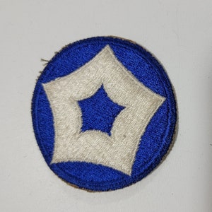 May include: A blue and white embroidered patch with a white star in the center of a white square. The patch is circular and has a white border.