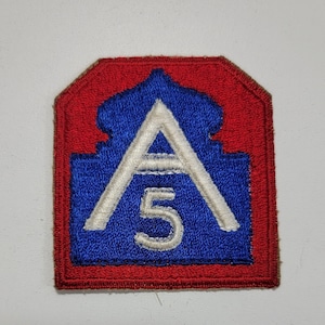 May include: A blue and red embroidered patch with a white letter "A" and the number "5" inside a white outline of a building. The patch is a military unit insignia.