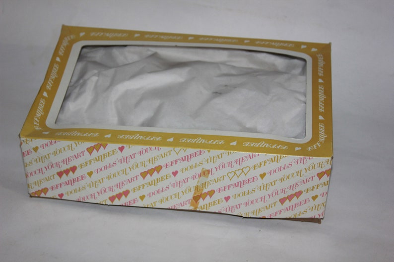 May include: A yellow and white cardboard box with a clear plastic window. The box is decorated with pink hearts and the text "EFFANBEE DOLLS THAT TOUCH YOUR HEART".